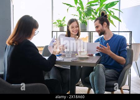 Gestionnaire de voyage de mariage, courtier immobilier, agent d'assurance bancaire travaillant avec un jeune couple Banque D'Images