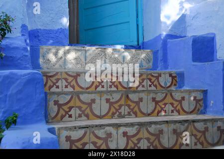 Chefchaouen, montagnes du Rif, escalier détaillé près d'une porte bleue dans un paysage architectural marocain, Maroc Banque D'Images