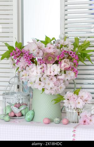 Arrangement de pâques avec un bouquet de cerise à fleurs japonaises, rose de carême, tulipe et bergenia et œufs de pâques Banque D'Images