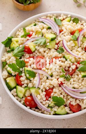 Salade de couscous perle avec des légumes frais et des herbes dans un bol de service, idée de plat d'accompagnement sain Banque D'Images