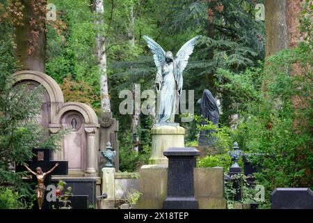 un ange sur un piédestal au milieu de tombes historiques dans les environs boisés du cimetière melaten de cologne Banque D'Images