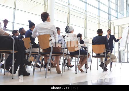 Vue d'angle bas de l'homme d'affaires biracial montrant des informations sur le tableau de conférence au groupe de gens d'affaires divers dans la salle de conférence Banque D'Images