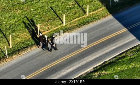 Ronks, Pennsylvanie 14 novembre 2023 - Un trio d'Amish, marchent le long d'une route de campagne, projetant de longues ombres dans le soleil de l'après-midi, parfait pour le style de vie et les thèmes communautaires. Banque D'Images