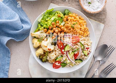 Bol repas végétalien avec légumes rôtis, laitue fraîche, lentilles cuites, salade de couscous et pois chiches grillés croustillants Banque D'Images