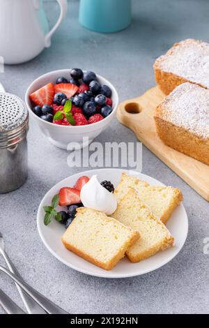 Gâteau traditionnel à la livre de vanille coupé en tranches et servi avec de la crème fouettée et des baies fraîches Banque D'Images