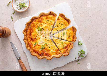 Quiche au saumon et au fromage aux herbes fraîchement cuites pour le petit déjeuner, tranchées sur une planche à découper Banque D'Images