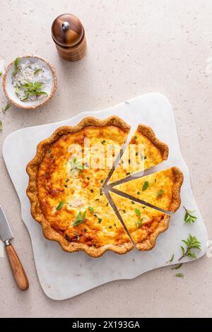 Quiche au saumon et au fromage aux herbes fraîchement cuites pour le petit déjeuner, tranchées sur une planche à découper Banque D'Images