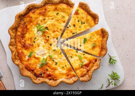 Quiche au saumon et au fromage aux herbes fraîchement cuites pour le petit déjeuner, tranchées sur une planche à découper Banque D'Images