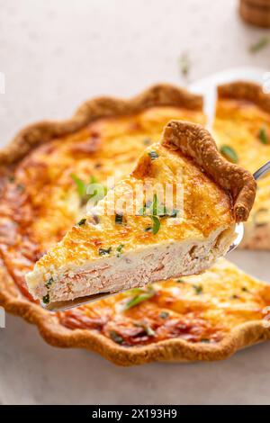 Quiche au saumon et au fromage aux herbes fraîchement cuites pour le petit déjeuner avec une tranche retirée Banque D'Images