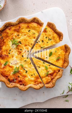 Quiche au saumon et au fromage aux herbes fraîchement cuites pour le petit déjeuner, tranchées sur une planche à découper Banque D'Images