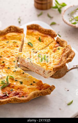 Quiche au saumon et au fromage aux herbes fraîchement cuites pour le petit déjeuner avec une tranche retirée Banque D'Images