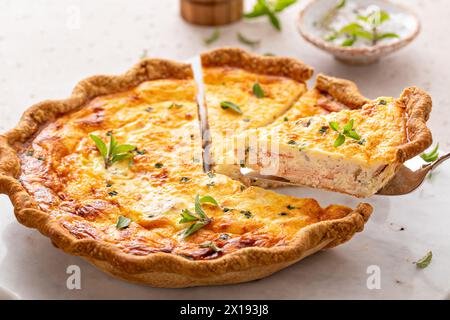 Quiche au saumon et au fromage aux herbes fraîchement cuites pour le petit déjeuner avec une tranche retirée Banque D'Images