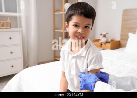 Petit garçon asiatique recevant le plâtre du médecin après vaccination dans la chambre Banque D'Images