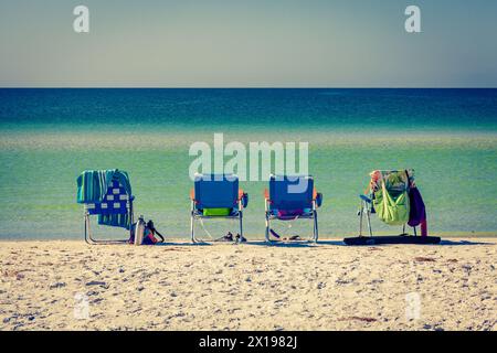 Chaise longue sur la plage en Floride avec les eaux calmes du golfe du Mexique en toile de fond. Banque D'Images