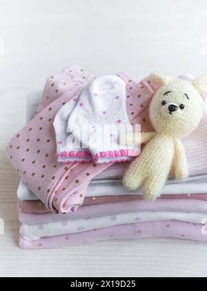 Pile de vêtements de bébé, chaussettes et jouet tricoté sur fond de bois blanc Banque D'Images