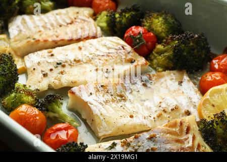 Morceaux de délicieuse morue cuite au four avec des légumes et des épices dans le plat, gros plan Banque D'Images