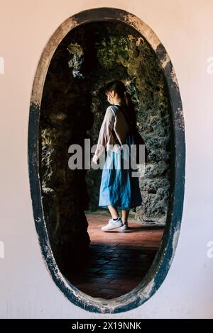 Une jeune femme visiteuse traverse une porte en forme d'œuf dans le jardin familial de Lin Ben Yuan dans le district de Banqiao, New Taipei City, Taiwan. Banque D'Images