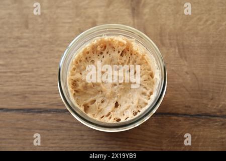 Levain de levain dans un pot en verre sur une table en bois, vue de dessus Banque D'Images