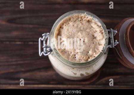 Levain de levain dans un pot en verre sur une table en bois, vue de dessus. Espace pour le texte Banque D'Images