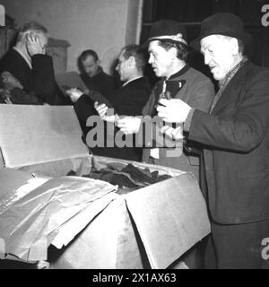 Action corrective américaine, don de vêtements à travers la croix rouge. Entrepôt, hommes qui retirent de la boîte, 20.12.1945 - 19451220 PD0006 - Rechteinfo : droits gérés (RM) Banque D'Images