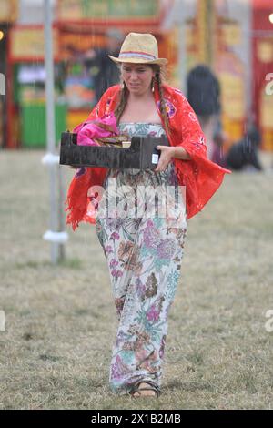 Un festivalier court à l'abri de la pluie pendant le festival WOMAD 2013, qui se tient à Charlton Park, Wiltshire. Banque D'Images