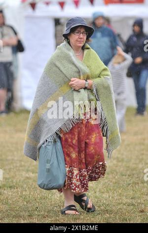 Un festivalier court à l'abri de la pluie pendant le festival WOMAD 2013, qui se tient à Charlton Park, Wiltshire. Banque D'Images