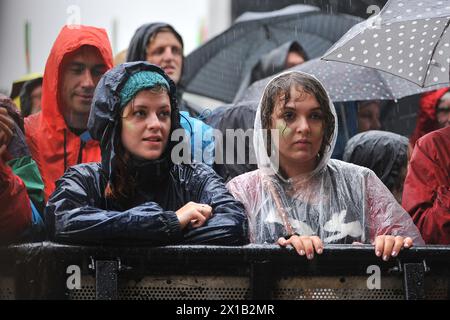 Les festivaliers bravent la pluie pour regarder des groupes se produire sur la scène principale lors du festival WOMAD 2013, qui se tient à Charlton Park, Wiltshire. Banque D'Images