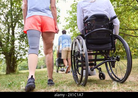 Une scène inclusive dans un parc avec deux amis, l’un en fauteuil roulant et l’autre avec une jambe prothétique, profitant d’une promenade par une journée ensoleillée. Banque D'Images
