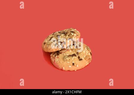 Plusieurs biscuits sablés saupoudrés de graines de tournesol sur le dessus reposent sur un fond rouge. Banque D'Images