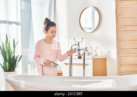 Une fille brune se prélasse dans une baignoire, se lavant diligemment les mains dans la salle de bain moderne. Banque D'Images