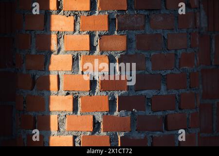 Motif de mur de briques rondes rouges avec des ombres profondes. Fond de photo abstrait avec mise au point sélective Banque D'Images