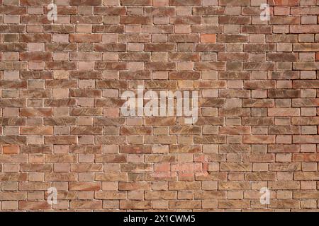 Les textures de mur de briques créent un motif qui s'étend horizontalement et verticalement le long du mur. Les nuances de rouge, variées par le temps et l'usure, ajoutent de la profondeur et Banque D'Images