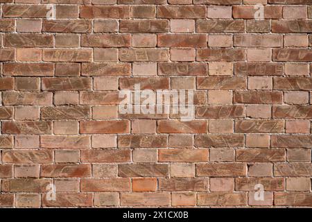 Les textures de mur de briques créent un motif qui s'étend horizontalement et verticalement le long du mur. Les nuances de rouge, variées par le temps et l'usure, ajoutent de la profondeur et Banque D'Images