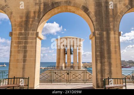 Le Mémorial de guerre de la cloche de siège encadré par une arche des jardins inférieurs de Barrakka, la Valette, Malte Banque D'Images