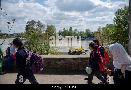 Les enfants de l'école marchent le long des rives de la rivière Jhelum tandis que les équipes de secours mènent une opération de recherche et de sauvetage sur le site de l'incident après qu'un bateau a chaviré à Srinagar. Un bateau transportant six individus, dont une femme et ses deux frères et sœurs, a chaviré en traversant la rivière enflée Jhelum à Srinagar. Le bateau, transportant au moins 15 personnes, pour la plupart des enfants, a fait six morts, et trois personnes sont toujours portées disparues. Les pluies continues des deux derniers jours, qui ont conduit à une élévation du niveau de l'eau dans la rivière Jhelum, ont conduit à la tragédie. Banque D'Images