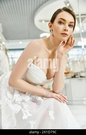 Une jeune mariée brune dans une robe blanche posant royalement pour une photo dans un salon de mariage. Banque D'Images