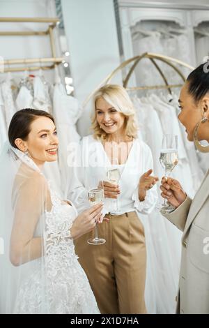 Trois femmes - une jeune mariée, sa mère d'âge moyen et une demoiselle d'honneur - se tiennent côte à côte, chacune tenant un verre de champagne. Banque D'Images