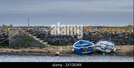 Bateaux à rames amarrés devant un mur du port dans un village anglais de pêche et de plaisance. Banque D'Images