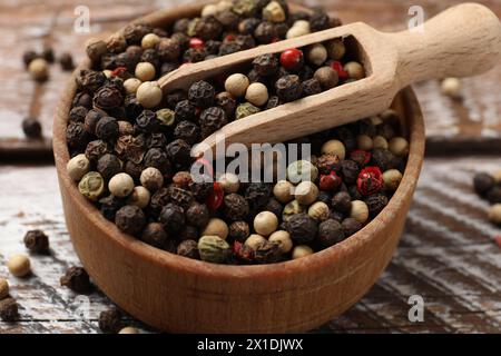 Épice aromatique. Différents poivrons dans un bol et une cuillère sur une table en bois, gros plan Banque D'Images