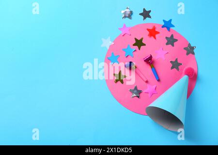 Chapeau de fête, confettis et souffleurs sur fond bleu clair, plat. Espace pour le texte Banque D'Images