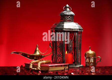 Lanterne arabe, Coran, misbaha et lampe magique Aladdin sur une table rouge brillante Banque D'Images