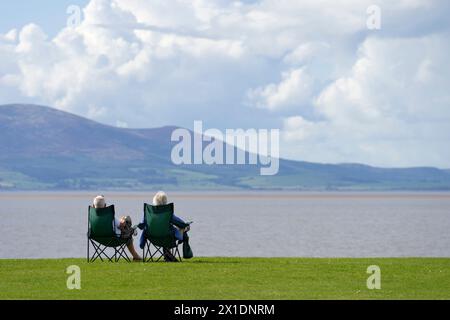 Couple se relaxant sur des sièges donnant sur le Solway Firth de Silloth, Cumbria, Angleterre Banque D'Images