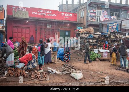 Un marché de rue animé à Kampala, en Ouganda, avec des vendeurs habillés de couleurs vives vendant des fruits, des légumes, de la volaille et plus encore. Une clinique dentaire et un téléphone Banque D'Images