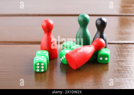 Dés verts et pièces de jeu de couleur sur la table en bois, gros plan Banque D'Images