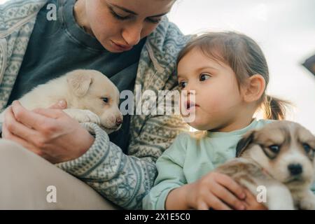 Femme et fille tenant des chiens chiots dans leurs bras et s'amusant ensemble. Chien comme un ami unit la famille, améliore la relation entre Banque D'Images