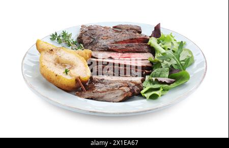 Morceaux de délicieuse viande de bœuf rôtie, poire caramélisée et légumes verts isolés sur blanc Banque D'Images