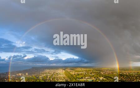 Herne Bay, Kent, Royaume-Uni. 16 avril 2024. Un panorama aérien d'un arc-en-ciel au-dessus de Herne Bay lors d'une averse de pluie après une journée ensoleillée et bleutée. Crédit : Jamie McBean/Alamy Live News Banque D'Images