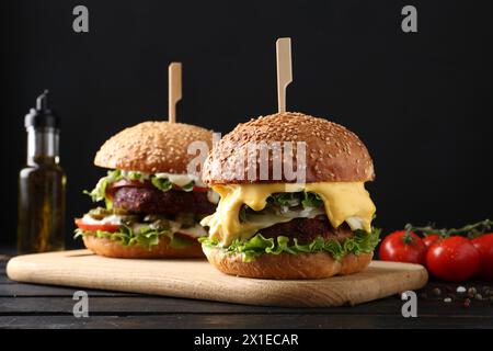 Hamburgers végétariens avec de délicieuses galettes sur une table en bois noir Banque D'Images