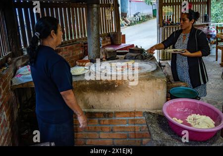 Mère et fille cuisinant une tortilla de maïs sur un poêle plat traditionnel. Oaxaca, Mexique. Banque D'Images