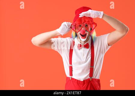 Portrait de clown avec des verres de nouveauté sur fond orange. Fête du fou d'avril Banque D'Images